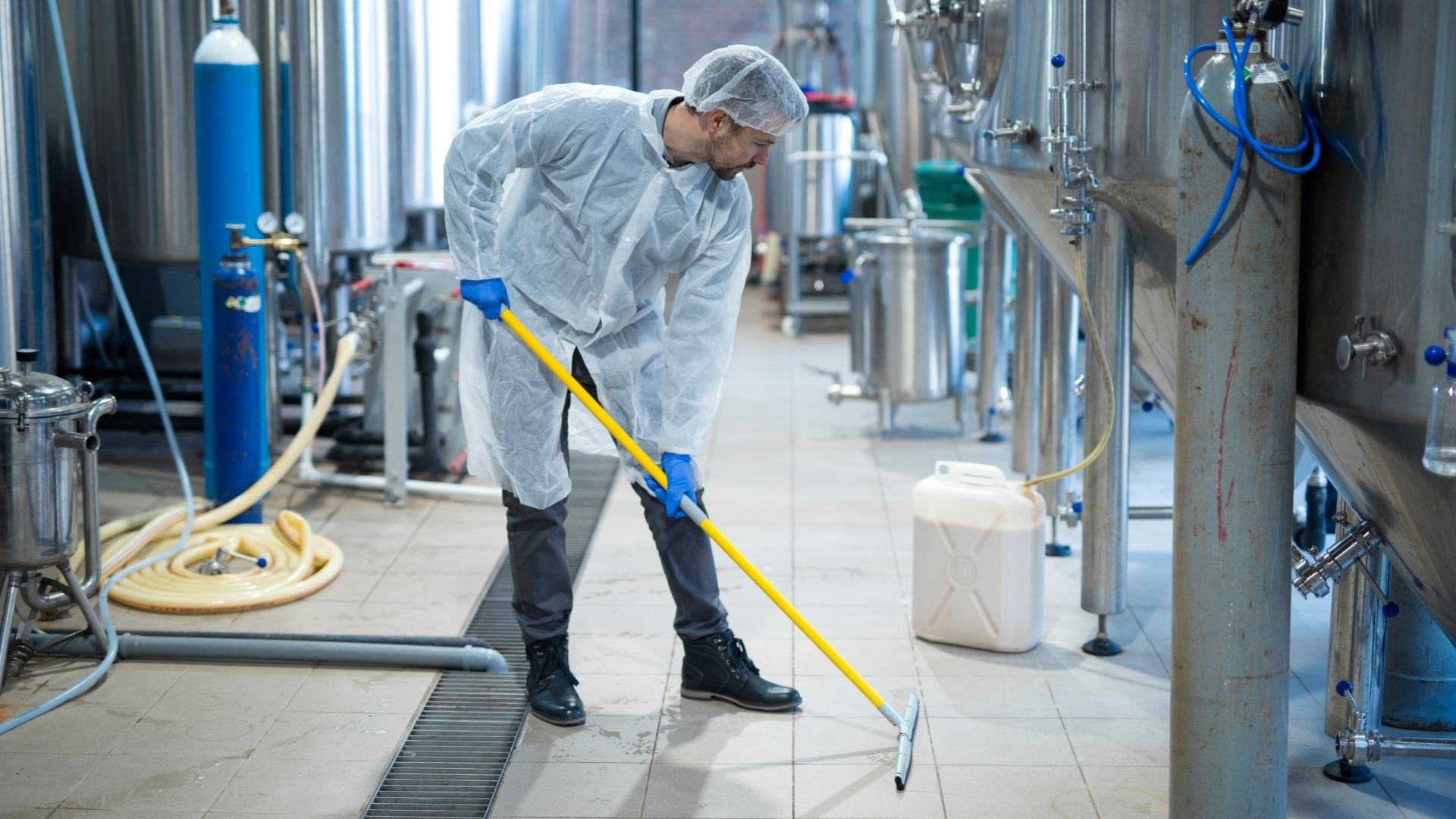 Mann putzt den Boden in einer Brauerei