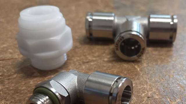 Verschiedene Pneumatik-Schottverschraubungen auf Holztisch